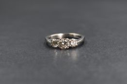 An 18ct white gold diamond set three stone ring, the central round brilliant cut diamond measuring