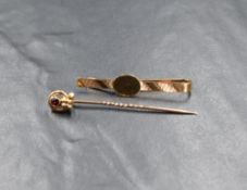 A 15ct gold ruby set stick pin, the oval cut bezel set ruby in an openwork knot setting motif