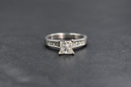 A platinum princess cut diamond solitaire ring having a 1ct princess cut diamond in a raised 4