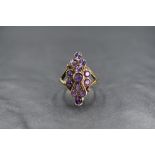 A 9ct gold amethyst set plaque ring, the central round cut amethyst in a twelve round cut amethyst