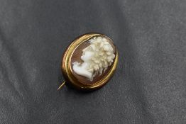 A yellow metal presumed gold cameo set brooch, the cameo depicting a maiden in profile, in a bezel