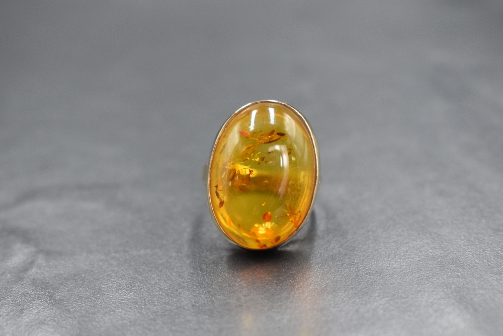 A 9ct gold amber set ring, the oval amber cabochon in a bezel setting having split shoulders, marked