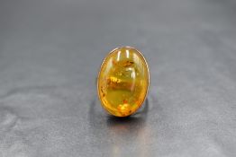 A 9ct gold amber set ring, the oval amber cabochon in a bezel setting having split shoulders, marked