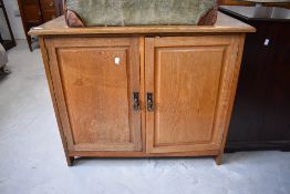 A 20th century oak two-door cabinet, having a shallow raised back and moulded rectangular top