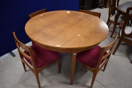 A 1980's circular extending dining table and four chairs, of functional design, 76cm x 1222cm