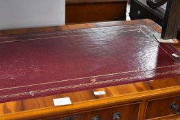 A reproduction yew wood pedestal knee-hole desk, of typical design with red-stained and gilt-