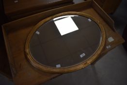 A reproduction gilt framed and bevelled oval wall mirror, of Regency design with bead, reeded and