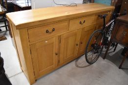 A large modern light oak sideboard, of oblong form with three frieze drawers over four panelled