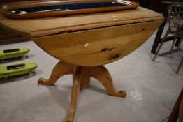 A modern pine pedestal drop-leaf dining table, with moulded edge detail, substantial central