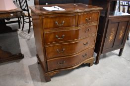 A reproduction figured mahogany serpentine-fronted chest of two short and three long graduating