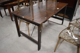 A vintage oak village hall style trestle table, of rectangular form, with hinged supports with metal
