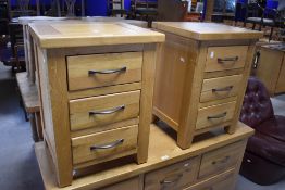 A pair of modern light oak bedside chests, the square panelled tops above three drawers, each with