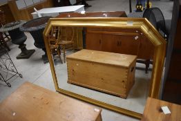 A large modern gilt framed and bevelled overmantel mirror, cushion moulded with canted upper corners