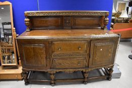 A large reproduction carved oak sideboard, having a raised, panelled and carved back with cup and