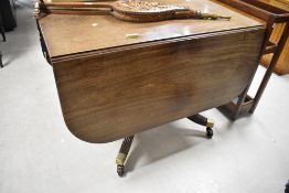 A 19th Century mahogany dining table in the Regency style having drop flaps and drawer to each end