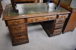 An early 20th century oak pedestal knee hole desk, the rectangular top with inset green-stained