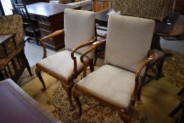 A pair of reproduction Queen Anne style armchairs, having padded backs and tapering drop-in seats