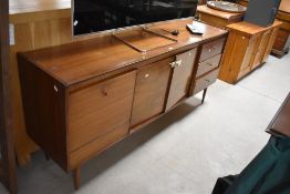 A 1960's walnut sideboard, of oblong form with two central cupboard doors flanked by three drawers