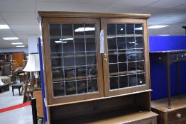 A 20th century glazed oak bookcase/display over cupboard, having a moulded cornice above two