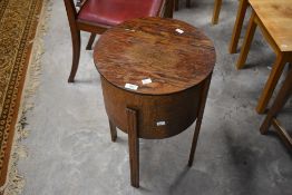 A 1940's oak sewing box, of circular form with hinged top enclosing the padded underside and