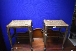 Two rush-seated stools, of typical design with turned legs linked by spindle stretchers 47cm x