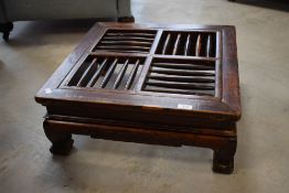 A Chinese low table, of square section form with spindled top over traditional design supports and