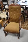 A Victorian mahogany scroll-arm rocking chair, with buttoned and padded back over the serpentine