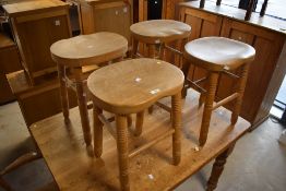 A set of four modern beech stools, each with rounded and dished seats raised on ring turned legs