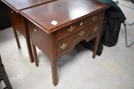 A reproduction mahogany lowboy, the moulded and banded rectangular top above an arrangement of long,