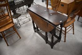 A traditional oak dining table having drop leaves and turned gateleg