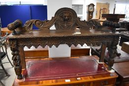 A Victorian carved oak hall bench, having a shaped and pierced back carved with central mask and