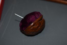 A small Victorian fancy work walnut shell pin cushion, a sweet, very small and tactile example,