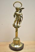 A tall Victorian brass and cast iron doorstop, featuring a cherub figure standing upon a pedestal,