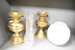Two late 19th to early 20th-century duplex brass oil lamps, both having glass chimneys; sold with