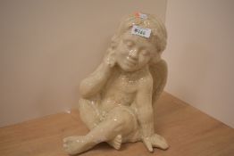 A decorative Victorian pottery cherub figurine with a crackle glaze finish, in a seated position,