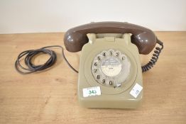A vintage GPO 706F-style rotary telephone, featuring a green plastic body with a brown handset,