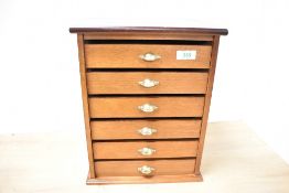 A mid to late 20th-century wooden tabletop collectors cabinet, having six green felt lined drawers