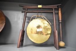 A presumed 20th-century brass dinner gong mounted upon a wooden tori gate-style tabletop stand,