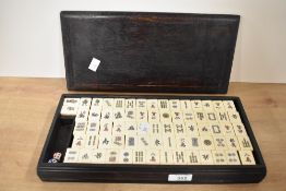 A vintage Mahjong set, with presumed animal bone and bamboo pieces, within a dark hard wood box,