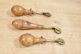 Three fine late 19th to early 20th-century brass pricking/scriveners wheels, featuring turned wooden