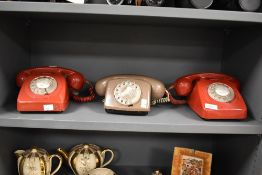 Three mid to late 20th-century rotary dial landline telephones, to include two red and one beige