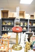 A Victorian brass oil lamp, having a cranberry glass reservoir with a fluted Corinthian-style