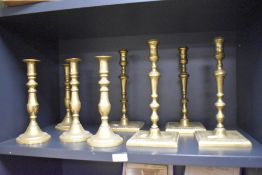 Two sets of four 19th-century brass candlesticks, each with baluster stems, one set with circular