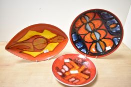 Three mid 20th-century Poole Pottery 'Delphis' plates and decorative dishes, featuring bold