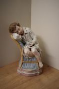 A continental polychrome Bisque figure, depicting a seated child asleep on serpentine parcel gilt