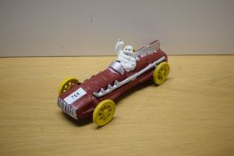 A painted cast model of Michelin Man in vintage racing car