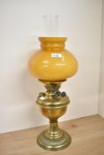 A 20th-century brass Duplex oil lamp, having an orb-shaped amber glass shade, marked, 52cm tall,