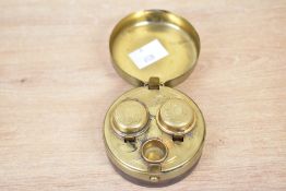 A Victorian brass travelling double inkwell, featuring a hinge puck-shaped leather and brass case