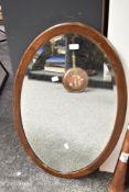 A large early to mid 20th-century mahogany oval wall mirror with bevelled glass, unmarked but