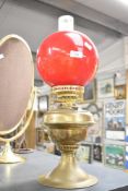 A Victorian brass and glass oil lamp, having ruby red glass globe shade, a clear glass chimney and